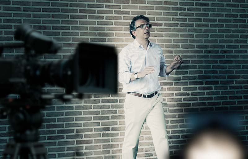 Filmregisseur Farid steht vor einer Mauer und gibt Anweisungen. Davor ist eine Filmkamera zu sehen.